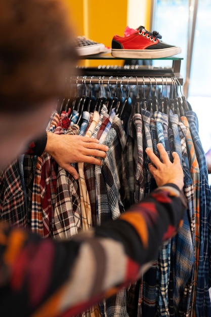 Achteraanzicht man kijken naar kleding in kringloopwinkel