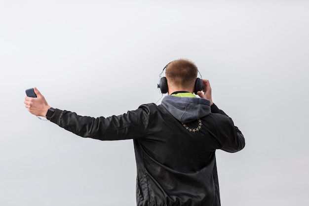 Gratis foto achteraanzicht man luisteren naar muziek buiten