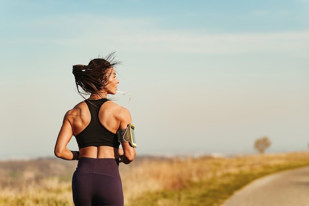 Gratis foto achteraanzicht van atletische vrouw die jogt tijdens het sporten in de natuur ruimte kopiëren