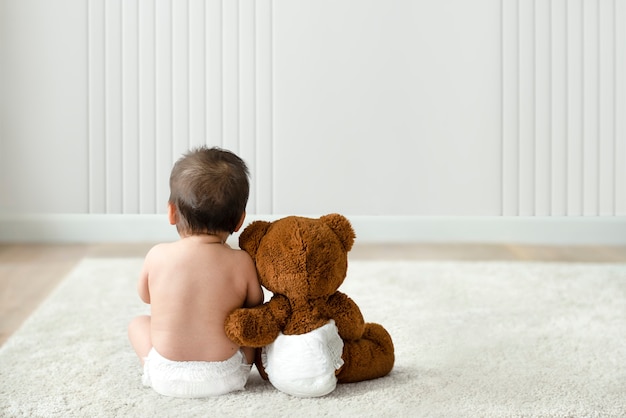 Gratis foto achteraanzicht van baby en teddybeer met ontwerpruimte
