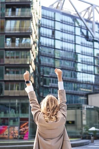 Gratis foto achteraanzicht van bedrijfsvrouwenadvocaat die de handen opheft en triomfeert om doel of succes te bereiken