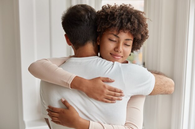 Achteraanzicht van blanke man omhelst haar vriendin, staat dicht bij elkaar, drukt liefde en steun uit, troost, drukt empathie uit, heeft goede relaties. Mensen, zorg en relatie concept