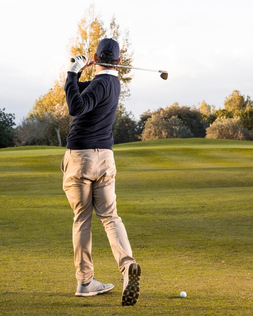 Achteraanzicht van de man spelen op het met gras begroeide golfveld