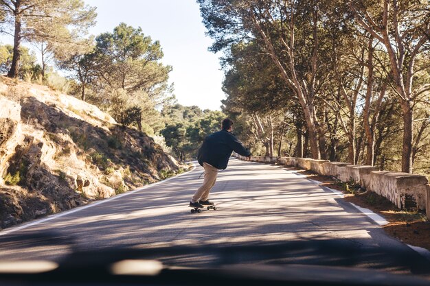 Achteraanzicht van de mens met skateboard op weg