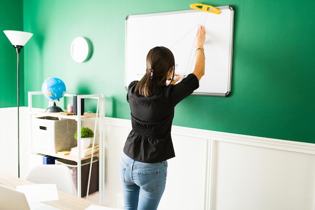 Gratis foto achteraanzicht van een jonge leraar die op een schoolbord schrijft en een wiskundeles geeft tijdens een virtuele les