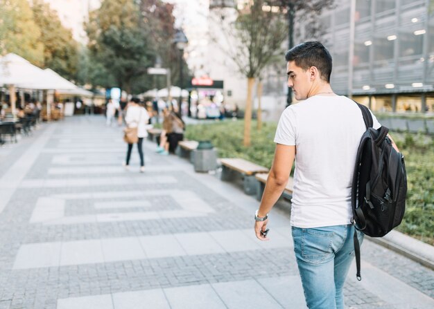 Achteraanzicht van een jonge man lopen op de stoep