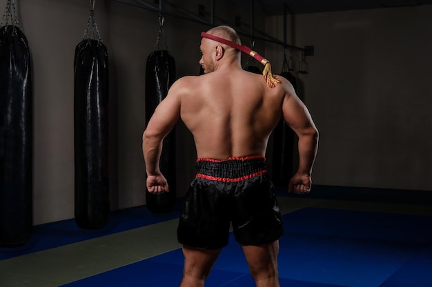 Achteraanzicht van een Muay Thai-jager met een gespierd lichaam traditioneel uniform in de sportschool