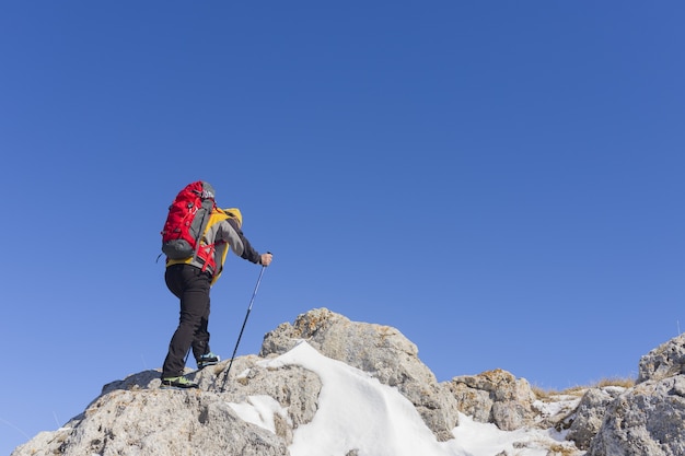 Achteraanzicht van een wandelaar die naar het uitzicht kijkt vanaf een besneeuwde bergtop