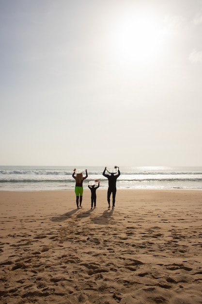 Achteraanzicht van familie met surfplanken boven hun hoofd