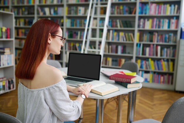 Achteraanzicht van het boek van de vrouwlezing in bibliotheek