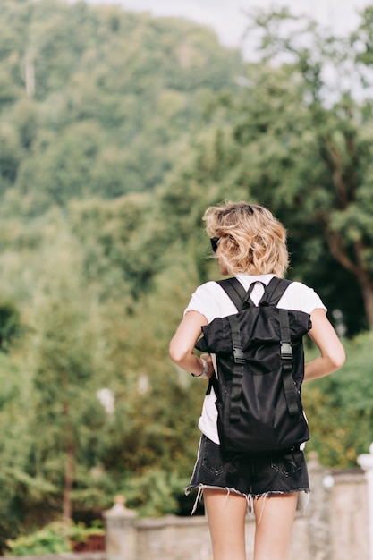 Gratis foto achteraanzicht van jonge mooie vrouw met kort kapsel met rugzak reizen in de bergen in zonnige goede dag, reis, avonturen, weg, ontspannen, vakantie