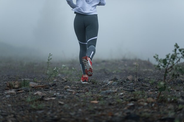 Achteraanzicht van onherkenbare atletische vrouw die in mistig weer loopt