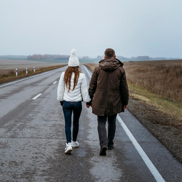 Achteraanzicht van paar hand in hand op de weg