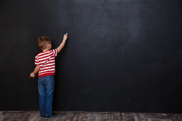 Achteraanzicht van schattige kleine jongen jongen schrijven met krijt