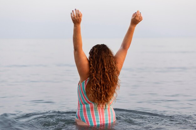 Achteraanzicht van vrouw in het water op het strand