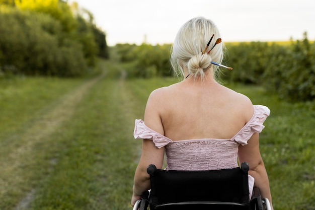 Gratis foto achteraanzicht van vrouw in rolstoel buitenshuis