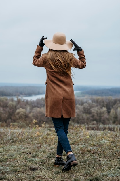 Gratis foto achteraanzicht van vrouw met hoed poseren in de natuur