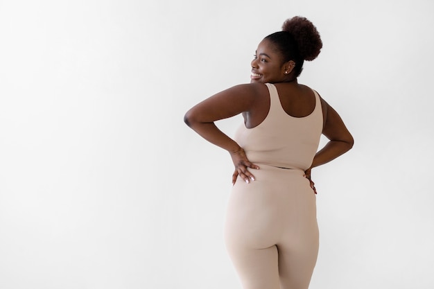 Achteraanzicht van zelfverzekerde smileyvrouw poseren terwijl het dragen van een body shaper met kopie ruimte