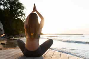 Gratis foto achteraanzicht vrouw doet yoga op het strand