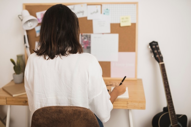 Gratis foto achteraanzicht vrouw schrijven in een notitieblok