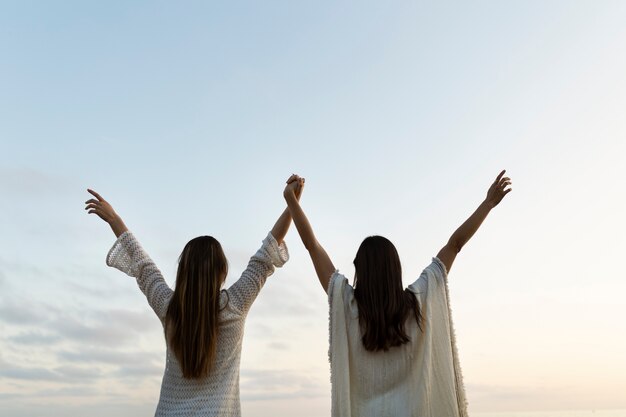 Achteraanzicht vrouwen hand in hand op het strand