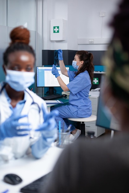 Gratis foto achtergrondfocus op verpleegster die beschermend masker en handschoenen draagt die klinische röntgen-ct-scanresultaten controleert tijdens dokter - patiënt sociale afstand medische controle in steriele kliniek