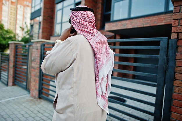 Achterkant van Arabische zakenman uit het Midden-Oosten poseerde op straat en sprak op mobiele telefoon