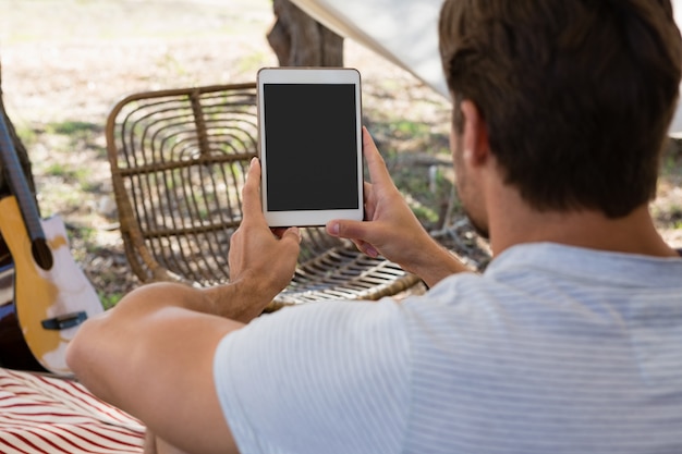 Achtermening van de jonge mens die tablet in tent gebruiken