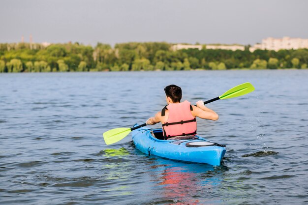 Achtermening van de mens die peddel voor het kayaking gebruiken