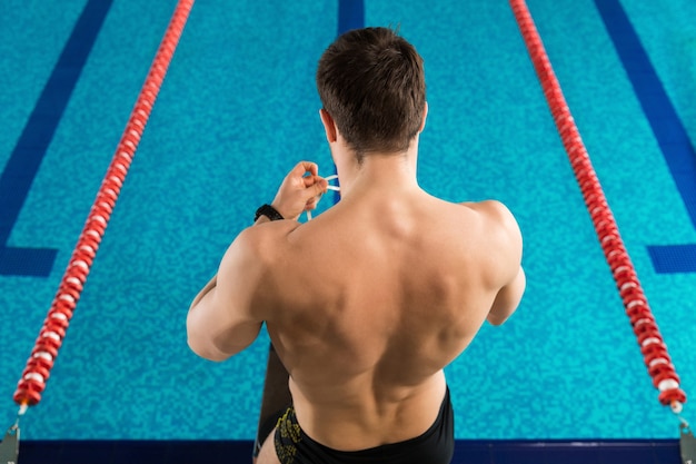 Achtermening van een mens die zwemmende beschermende brillen voorbereiden