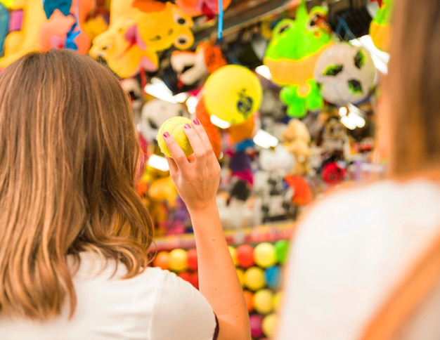 Achtermening van een vrouw die naar speelgoed met tennisbal streven