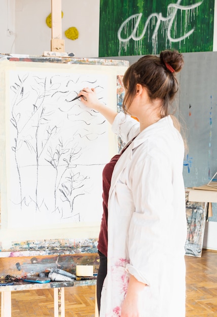 Achtermening van vrouwelijke kunstenaarstekening op canvas met houtskoolstok