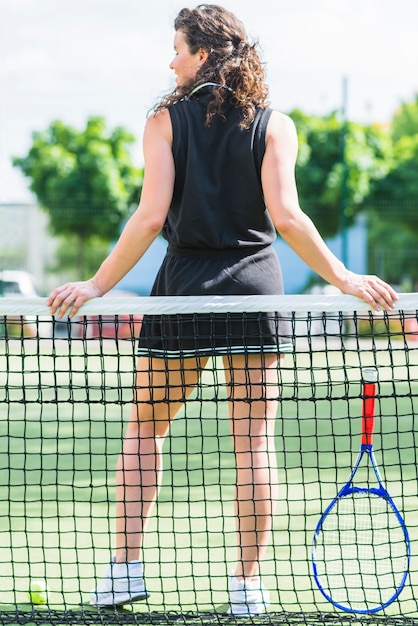Achtermening van vrouwelijke speler achter tennisnet