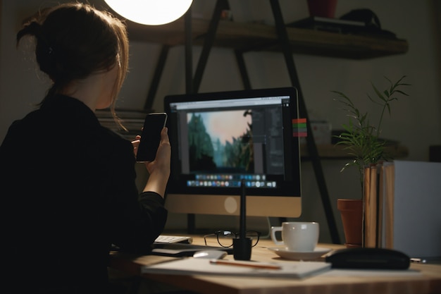 Achtermeningsbeeld van jonge vrouwenontwerper die telefonisch babbelen.