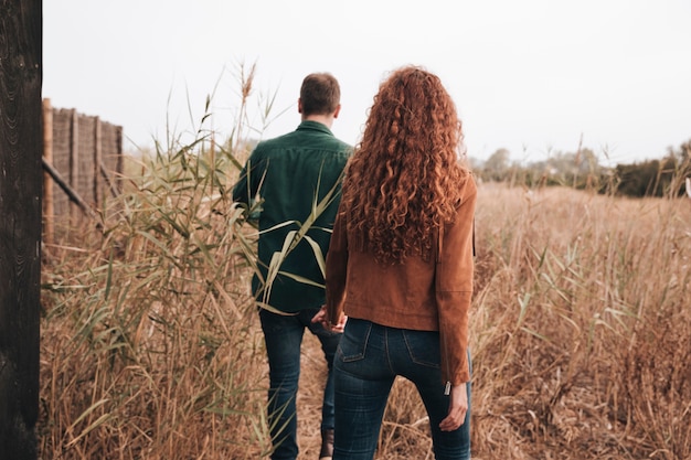 Gratis foto achtermeningspaar die door tarwegebied lopen