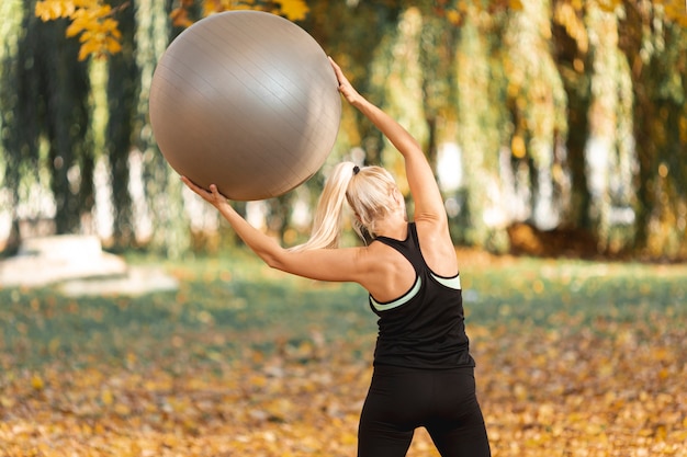 Achtermeningsvrouw die een gymnastiekbal gebruiken