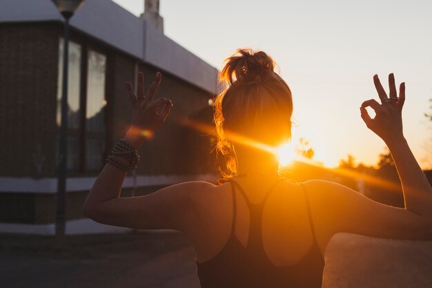 Achtermeningsvrouw die op zonsondergang mediteren