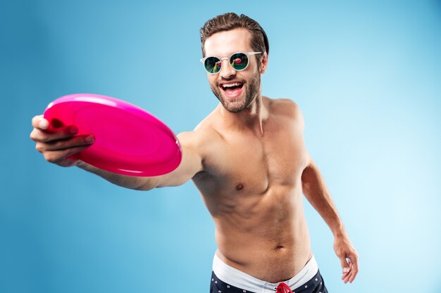 Actieve jonge man in zomer kleding gooien frisbee schijf