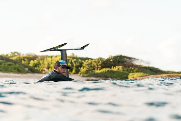 Gratis foto actieve man in speciale uitrusting die op een surfplank verblijft