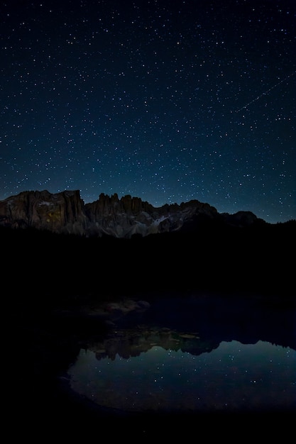 Gratis foto adembenemend landschap van de sterrenhemel en rotswanden die 's nachts op het meer reflecteren