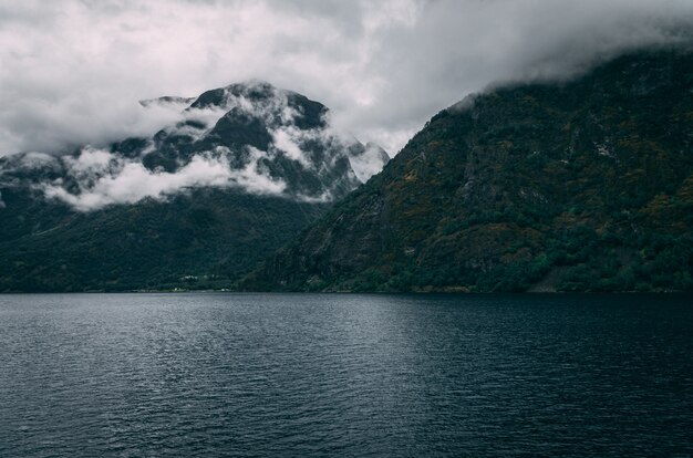 Adembenemend schot van een meer omringd door de besneeuwde bergen onder de mistige hemel in Noorwegen