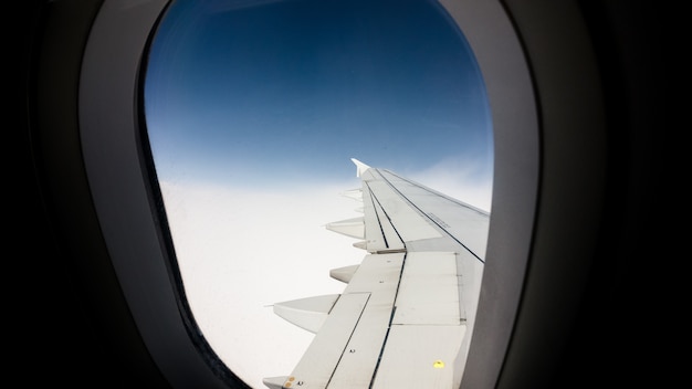Adembenemend uitzicht op de blauwe lucht vanuit het raam van een vliegtuig