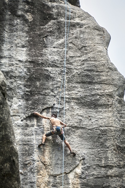 Gratis foto adembenemende foto van een jonge man die op de hoge rots in champfromier, frankrijk klimt