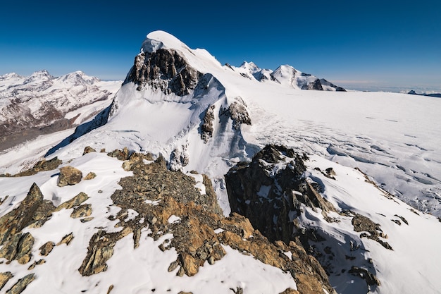 Adembenemende opname van de met sneeuw bedekte rotsachtige bergen onder een blauwe lucht