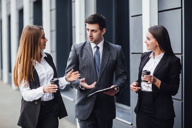 Afbeelding drie zakenpartners in een zwart, elegant pak die praten en samenwerken terwijl ze een nieuwe strategie bespreken!