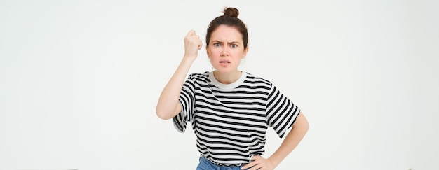 Gratis foto afbeelding van een boze vrouw die dreigt haar vuist te schudden met afkeuring en iemand uitscheldt die over wit staat