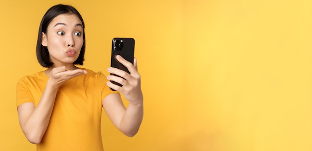 Afbeelding van een gelukkig, mooi Aziatisch meisje dat videochat en praat over een smartphone-applicatie die ertegen staat