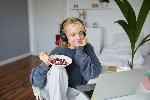 Gratis foto afbeelding van een gelukkige vrouw die in een kamer zit en een interessante tv-show of film kijkt op een laptop met behulp van