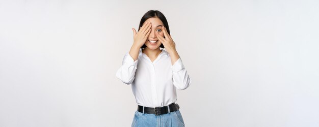 Afbeelding van een jonge aziatische vrouw sluit haar ogen en glimlacht, wacht op verrassing en verwacht door te gluren