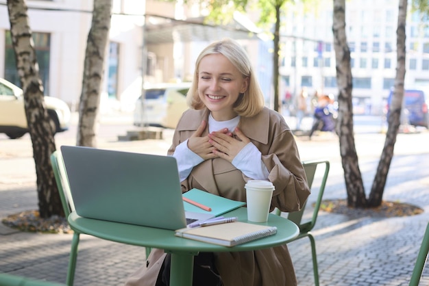 Gratis foto afbeelding van een jonge glimlachende vrouw die op afstand werkt, verbindt zich met online gesprekken via een laptop
